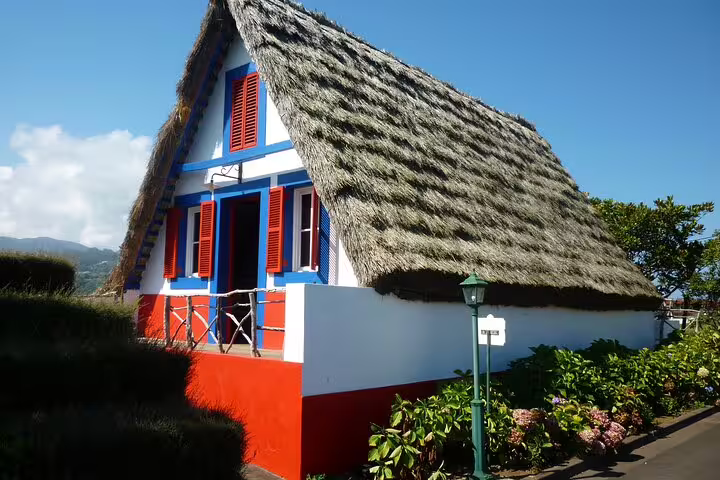 Traditional Santana house with a thatched roof surrounded by lush greenery on Madeira Island.