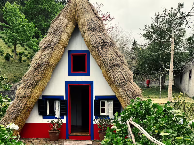 Traditional Santana house with a thatched roof in Madeira, surrounded by lush greenery, perfect for a private tour exploration.