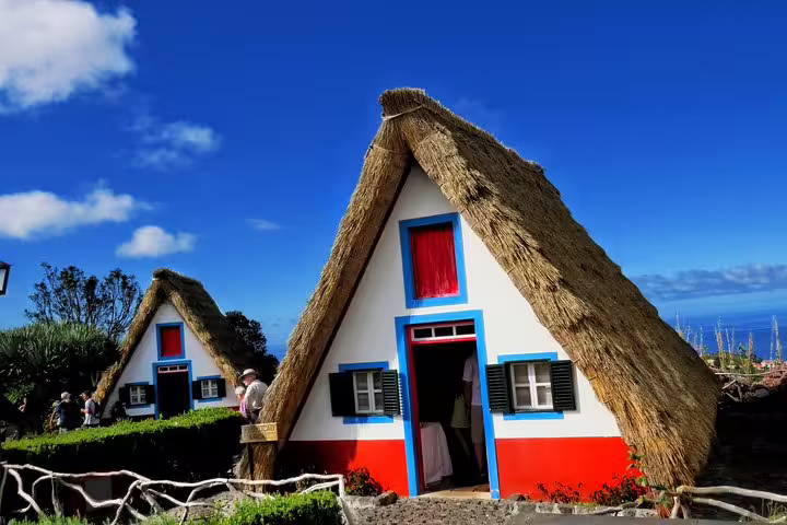 Traditional Santana houses with thatched roofs under a clear blue sky in Madeira, showcasing unique architecture and cultural heritage.