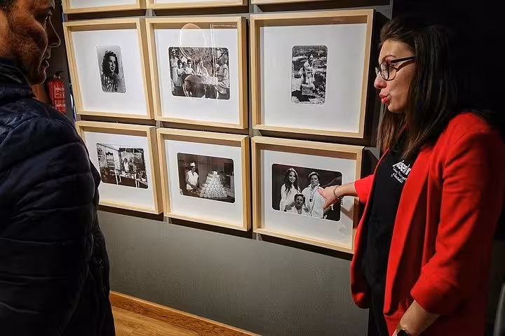 Tour guide explaining historical photographs to a visitor in a cultural exhibit on the Santander gastronomy tour.