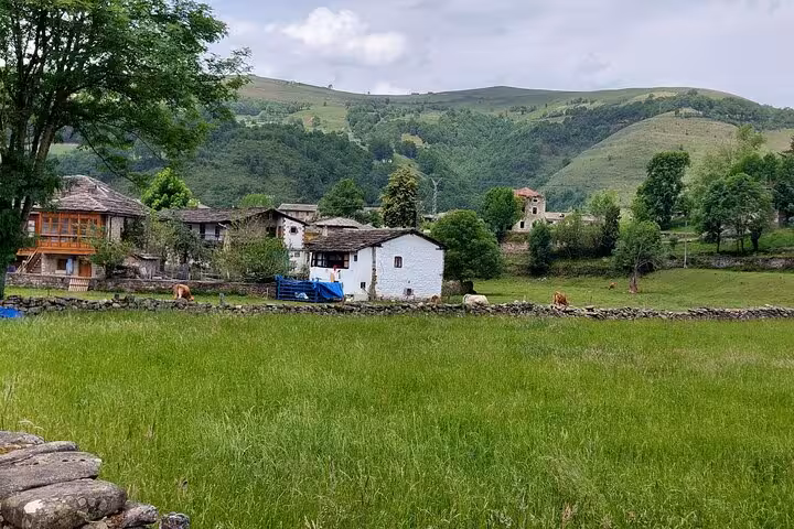 Charming rural landscape near Santander with traditional houses and lush green fields on a gastronomy tour route.