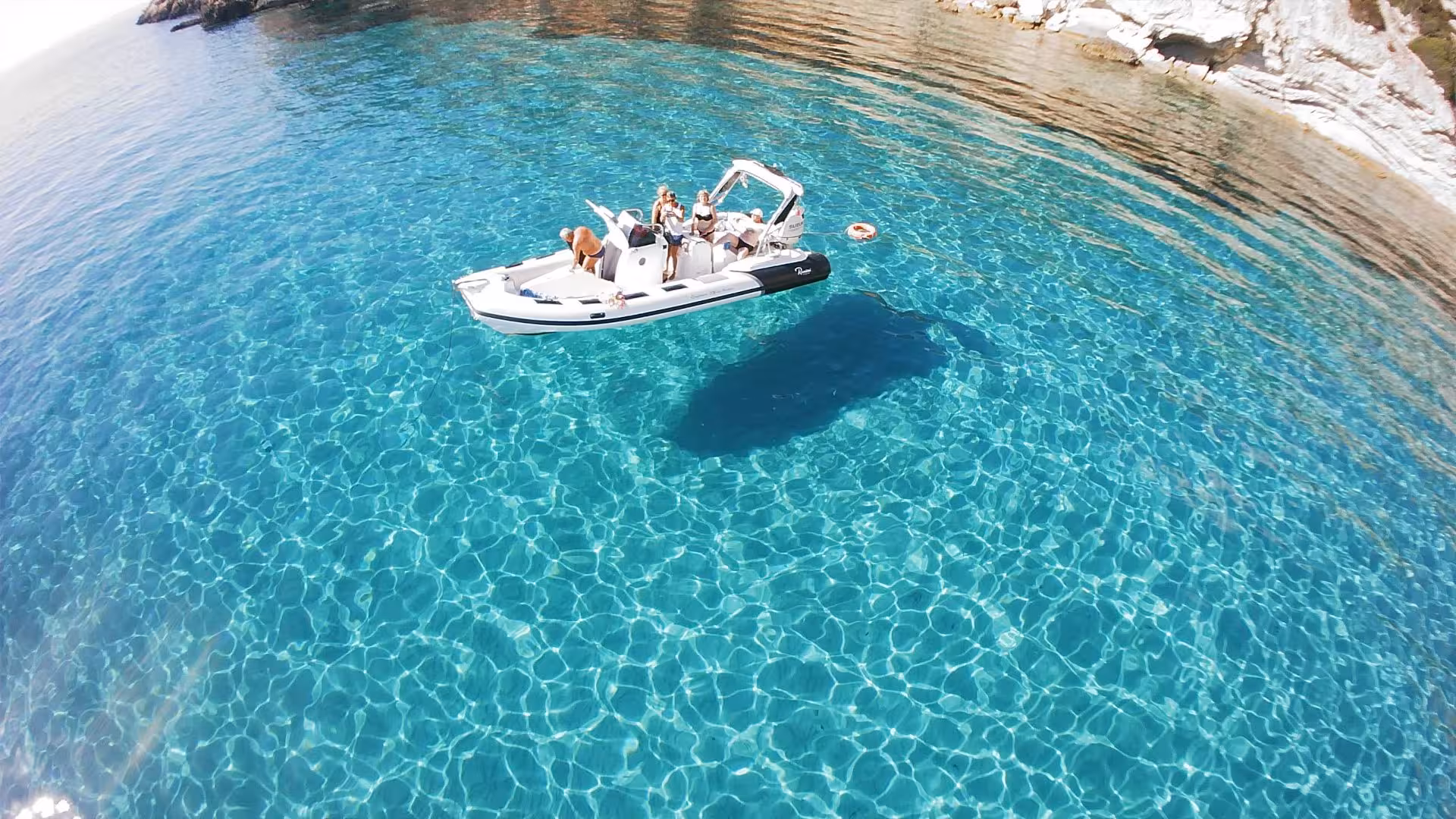 Aerial view of a RIB boat with tourists enjoying Sant'Antioco's crystal-clear waters on a scenic 4-hour tour.
