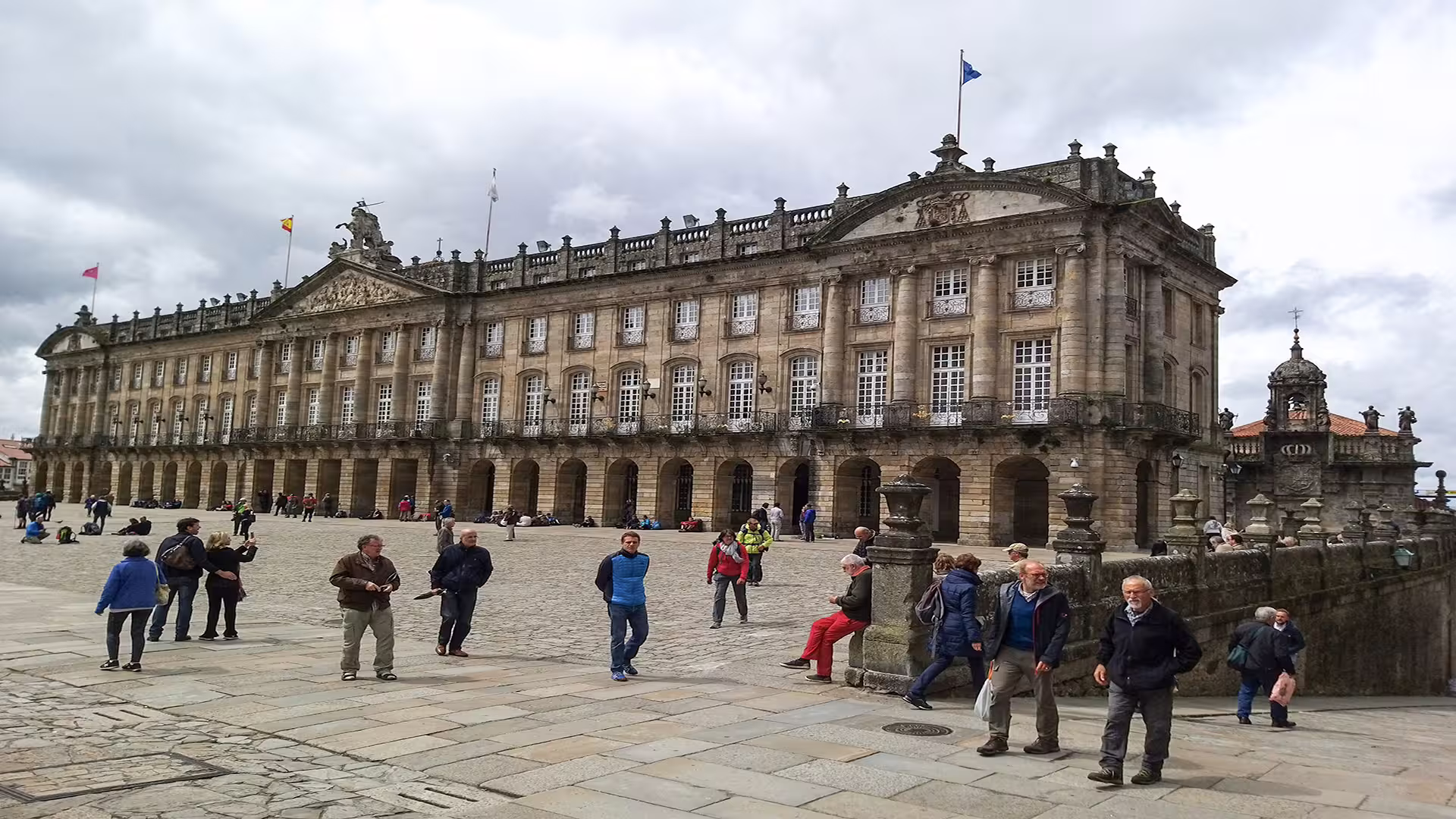 Tourists explore the historic square near Santiago de Compostela Cathedral, showcasing its grand architecture and cultural allure.