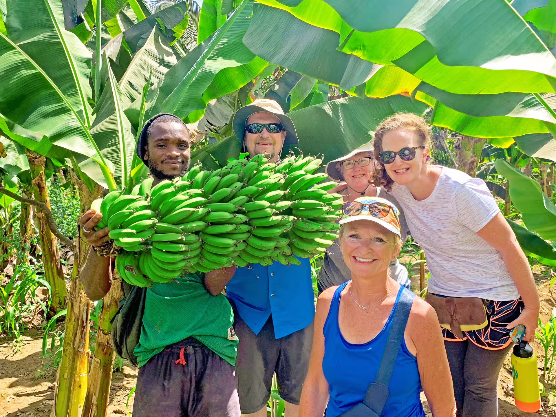 Tourists and local guide holding fresh bananas on Santiago Island plantation tour and workshop.
