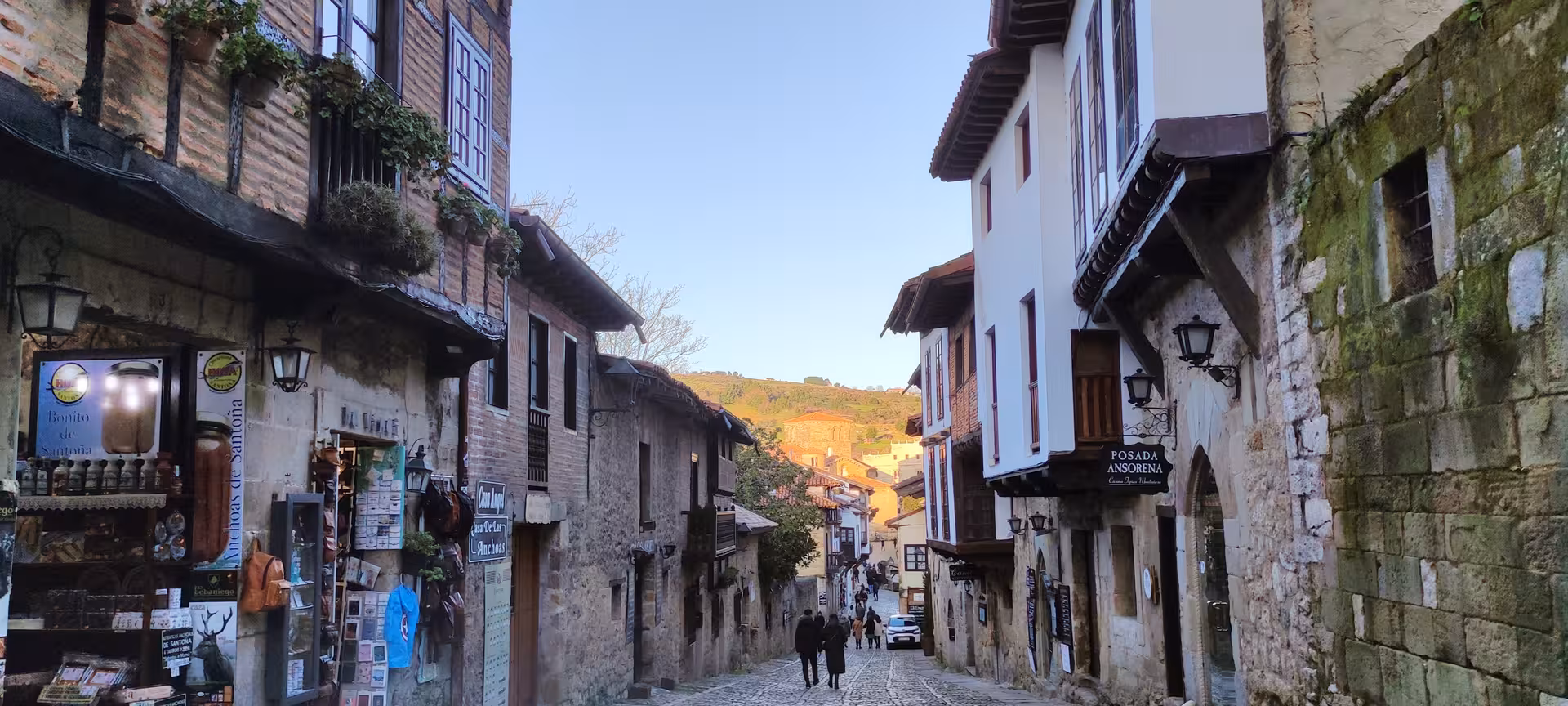 Picturesque cobblestone street in Santillana del Mar, lined with rustic shops and historical architecture.