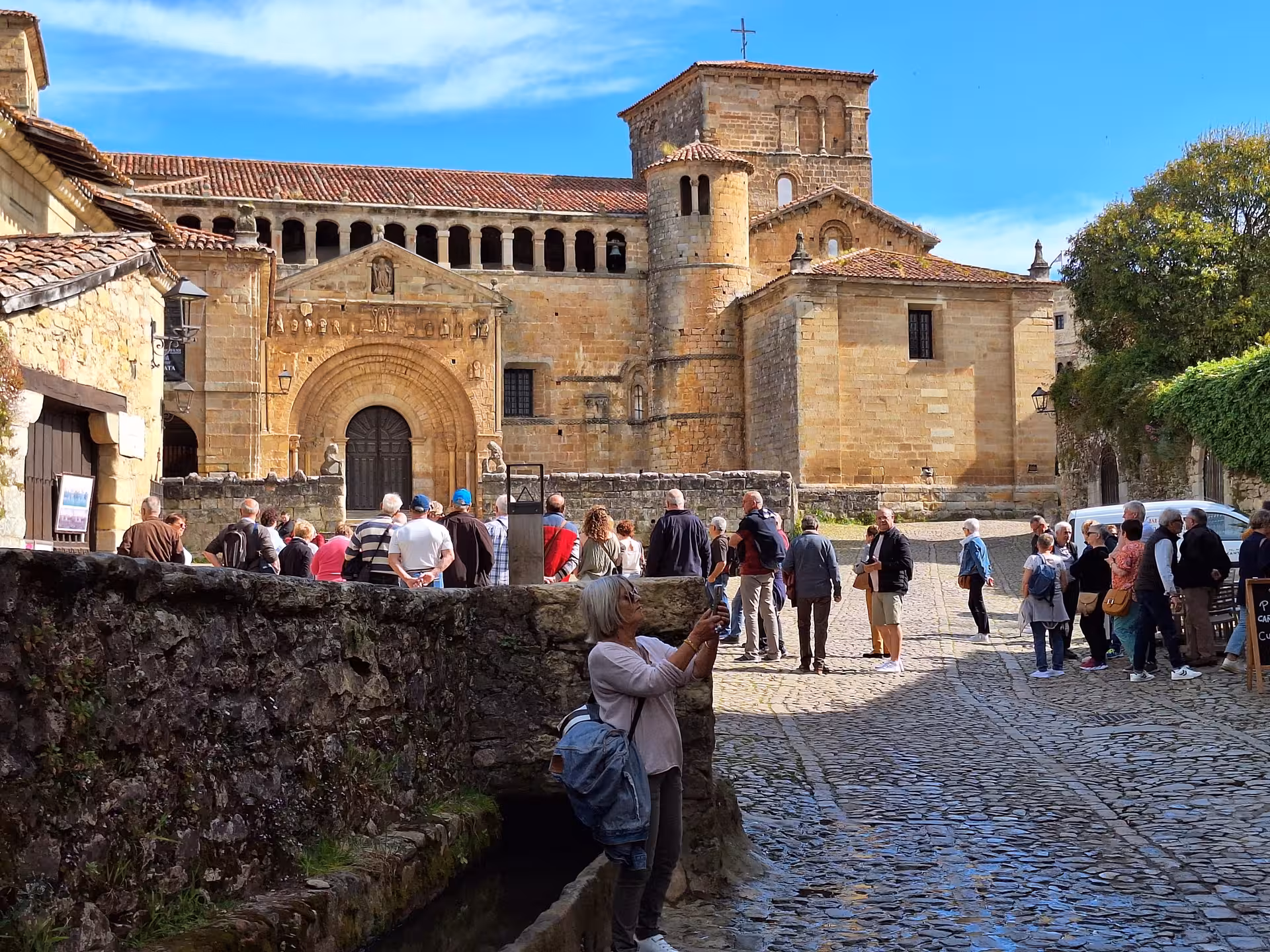 Tourists explore the historic cobblestone streets and ancient architecture of Santillana del Mar on a guided tour.