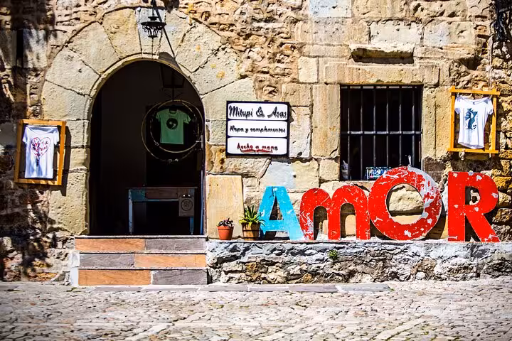 Charming stone building in Santillana del Mar with colorful 'Amor' sign, highlighting local culture and art.