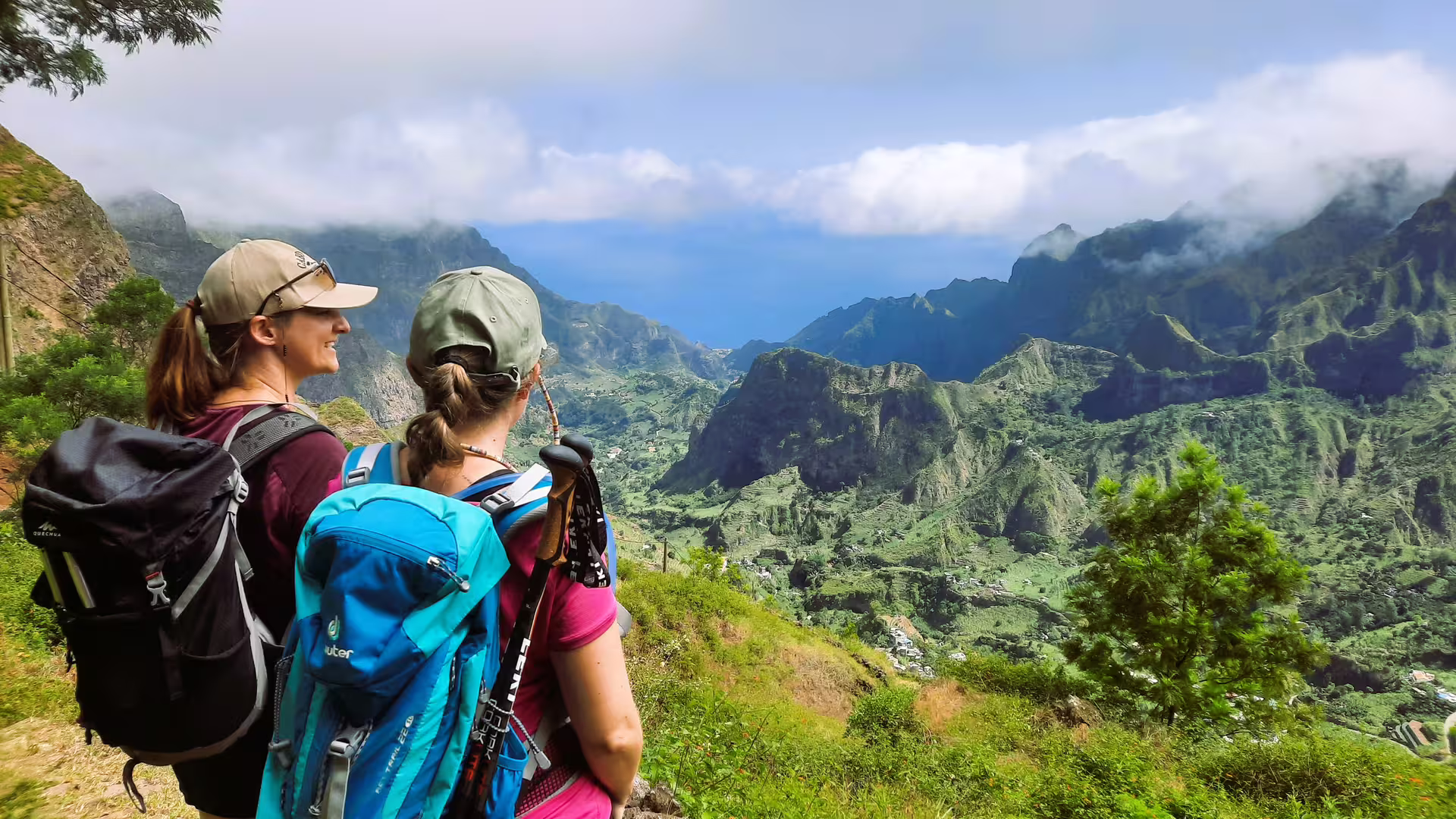 Two hikers enjoy the breathtaking view of Cova de Paúl Volcano Crater, surrounded by lush mountains in Santo Antão.