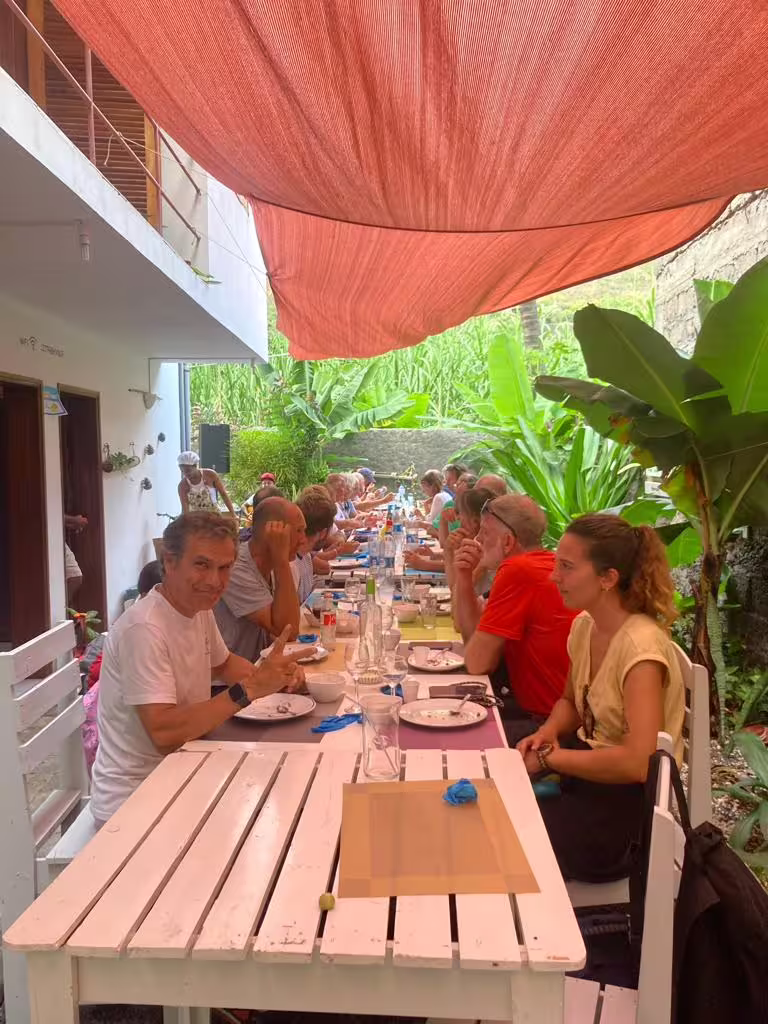 Travelers enjoy a communal meal under a canopy surrounded by lush greenery on a Santo Antão day trip from São Vicente.