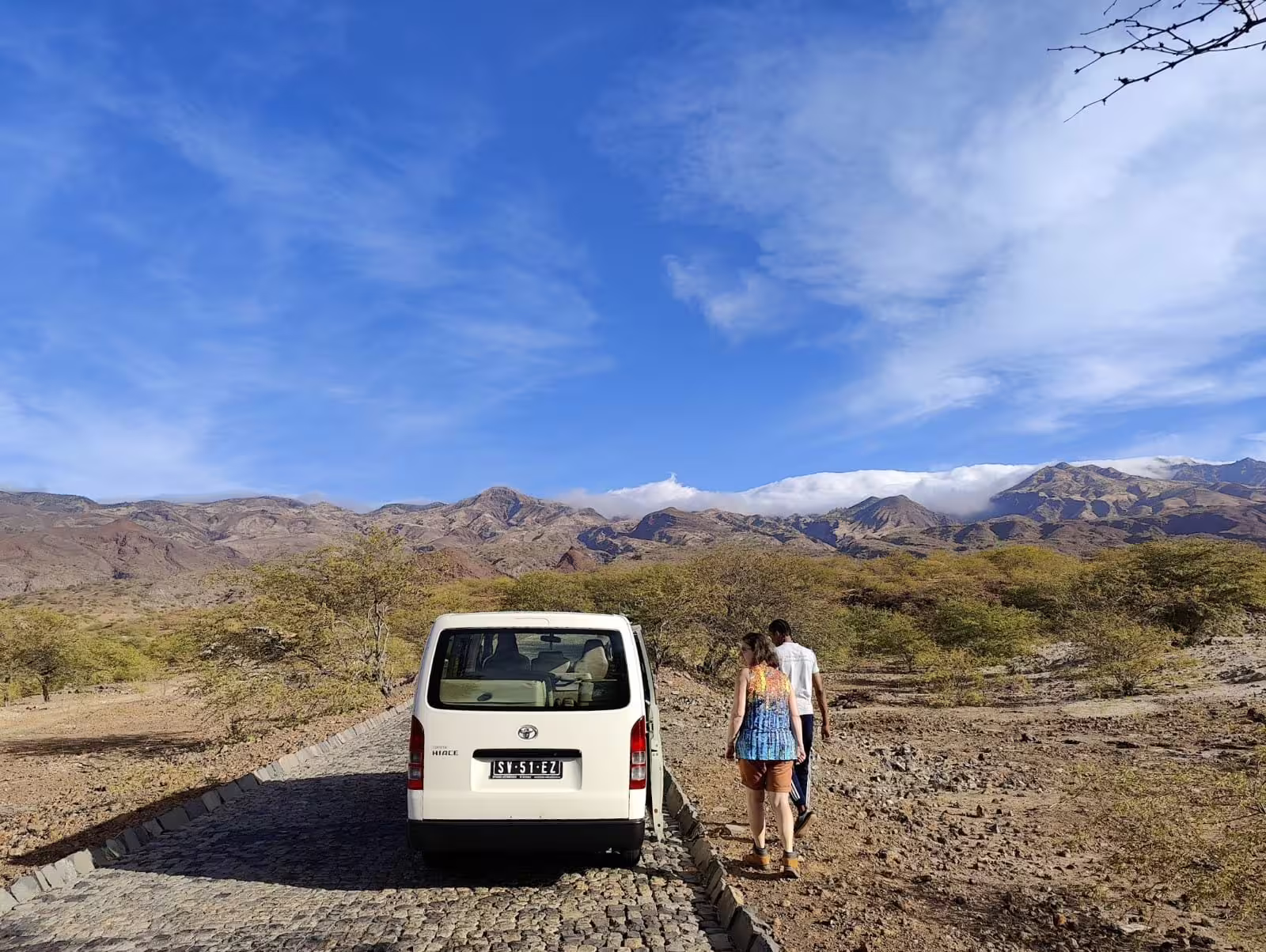 Van on a scenic cobblestone road with travelers exploring the rugged landscapes of Santo Antão, Cape Verde under a clear blue sky.
