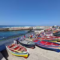 Colorful fishing boats lined up along the vibrant coastline of Santo Antão, Cape Verde, under a clear blue sky.