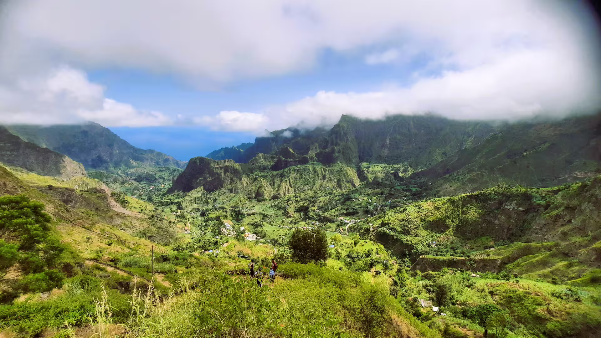 Panoramic view of Santo Antão's lush green valleys under a bright blue sky, perfect for trekking adventures.