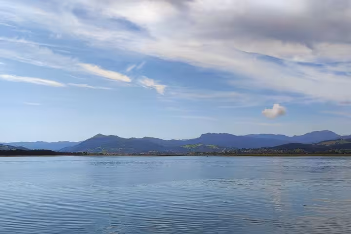 Scenic view of tranquil waters and distant mountains on a clear day in Santoña, perfect for a relaxing boat trip.