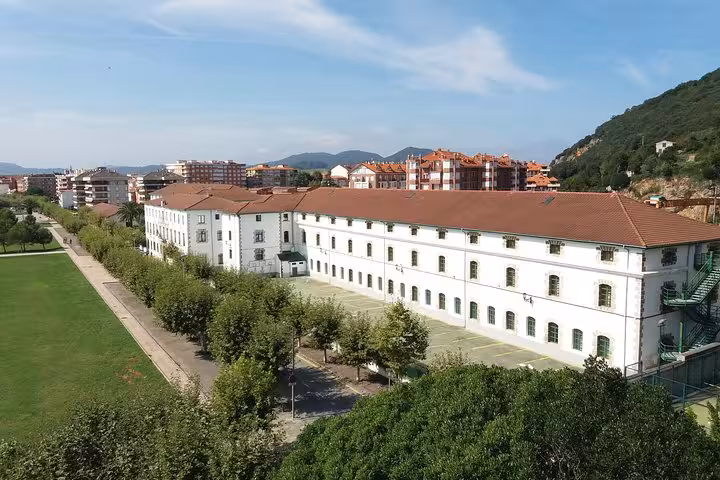 Historic anchovy factory in Santoña surrounded by greenery, showcasing traditional Spanish architecture.