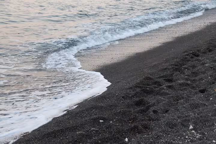Santorini black sand beach shoreline with gentle waves, a scenic stop on a private half-day island tour