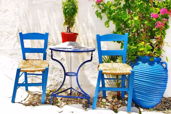 Blue chairs and table in a Santorini courtyard with bougainvillea, highlight of 2-day tour from Athens