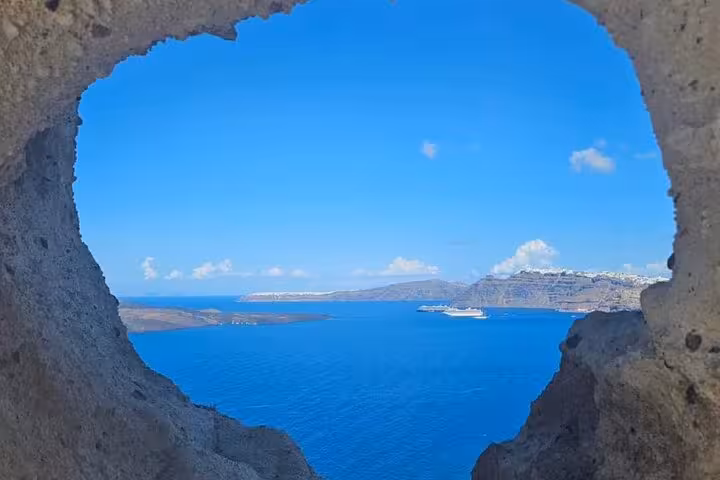 Santorini caldera and Aegean Sea view through a rock window, perfect photo stop on a one-day Santorini escape tour