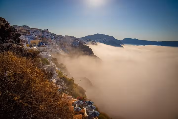Morning fog rolling over Santorini Caldera cliffs near Fira, scenic viewpoint on One Day Escape to Enchanting Santorini