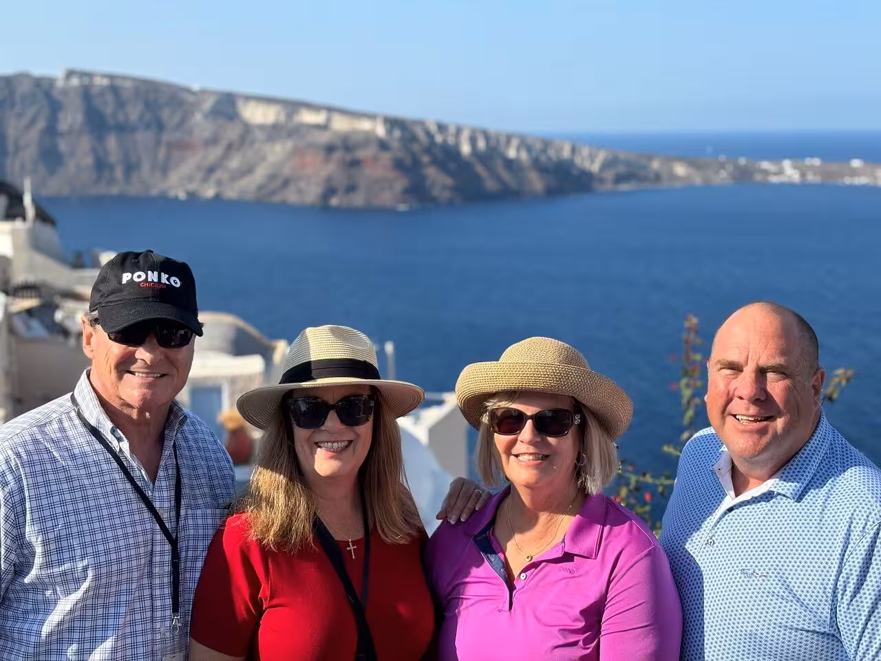Cruise guests pose by Santorini caldera cliffs on a private highlights tour and shore excursion photo stop