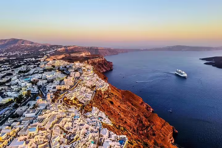Aerial view of Santorini caldera cliffs and cruise ship at sunset on a 3-day private tour from Athens