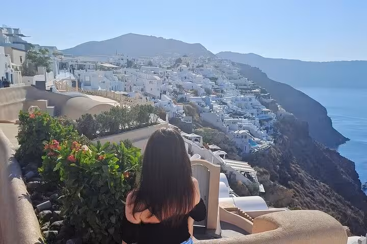 Traveler overlooks Santorini caldera in Fira, whitewashed cliffside villas on a cruise ship day tour