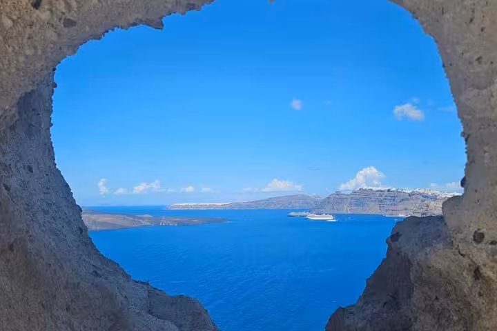 Santorini caldera sea view through volcanic rock arch, scenic stop on day getaway with luxury villa transport