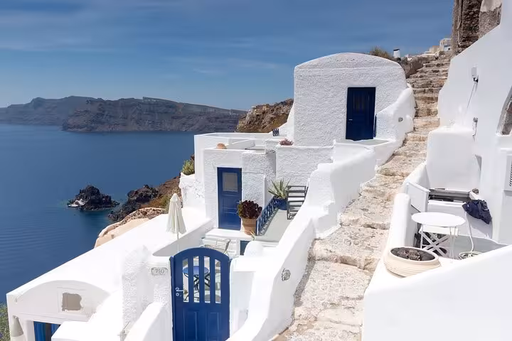 Santorini caldera view with white cave houses and blue doors, part of 2-day Athens to Santorini and Mykonos tour