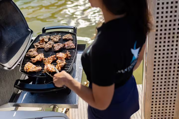Onboard chef grilling a delicious meal on a luxury catamaran during a Santorini cruise with open bar.