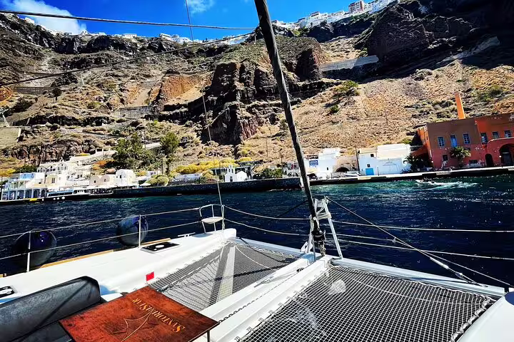 View from catamaran deck showing the stunning cliffs and architecture of Santorini's coastline.
