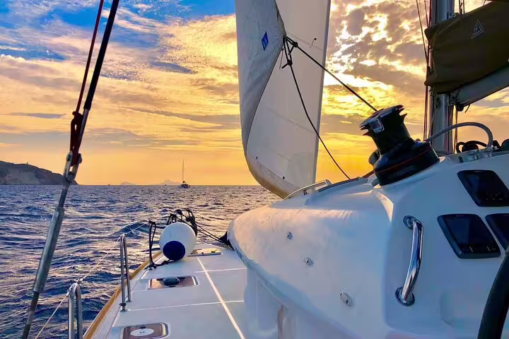 Sailing into a vibrant sunset on a catamaran cruise in Santorini, highlighting a serene sea journey.