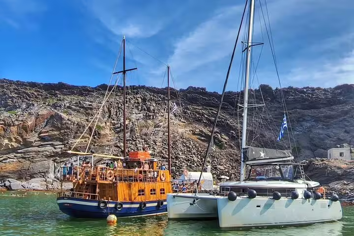 Sail alongside traditional wooden boats on a tailor-made catamaran cruise in Santorini's scenic coastline.