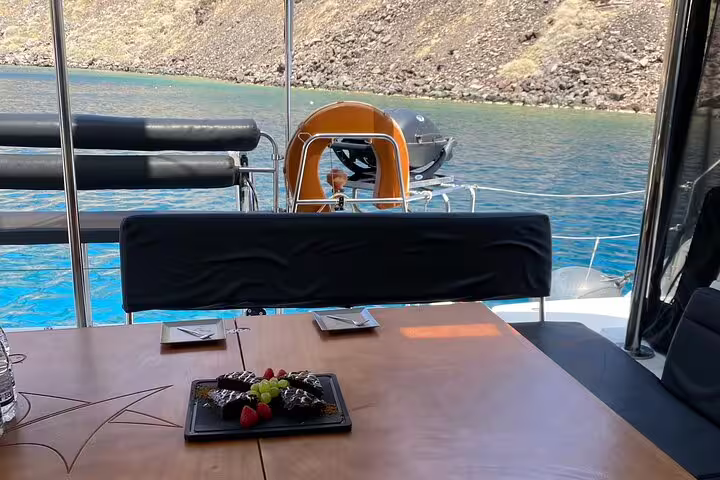 Enjoy a gourmet dining experience aboard a catamaran with views of Santorini's crystal-clear waters.