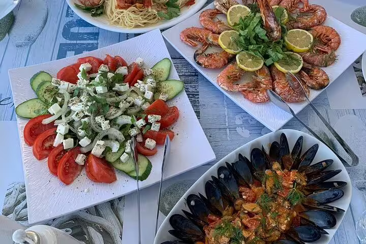 Delicious seafood and fresh Greek salad spread on a catamaran during a Santorini private cruise experience.
