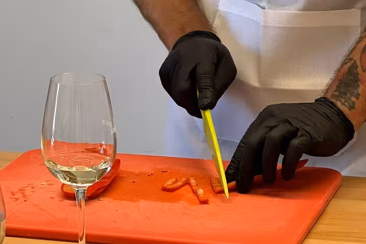 Chef slicing fresh vegetables beside a glass of Santorini wine during a private Greek cooking class