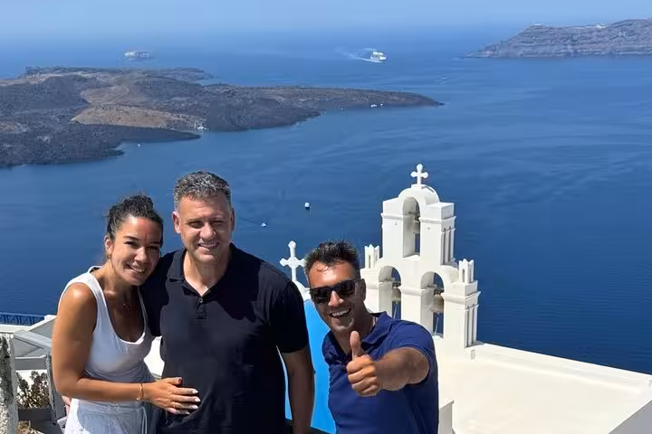 Group photo by Santorini white church overlooking caldera during private island tour and cooking class experience