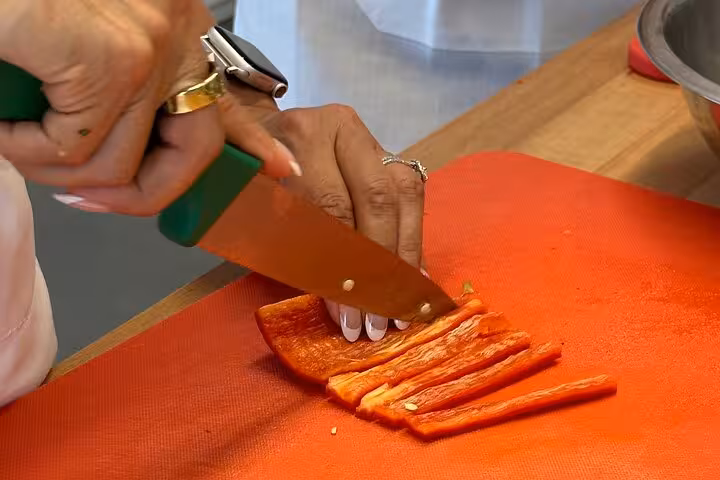 Slicing fresh red pepper during Santorini private cooking class, hands-on Greek meze prep on island tour
