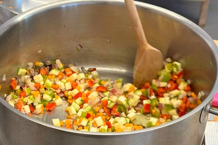 Chopped vegetables sautéing in a pot during a Santorini private cooking class and island tour experience