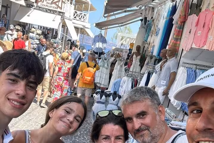 Cruise ship Santorini day tour stop at Fira market street, shoppers browsing Greek dresses and souvenirs