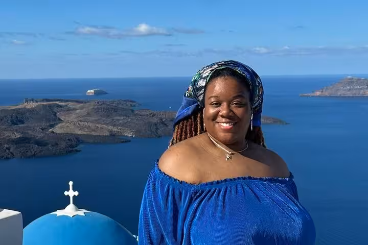Traveler at Santorini caldera viewpoint with blue dome church and Aegean sea, perfect cruise shore excursion