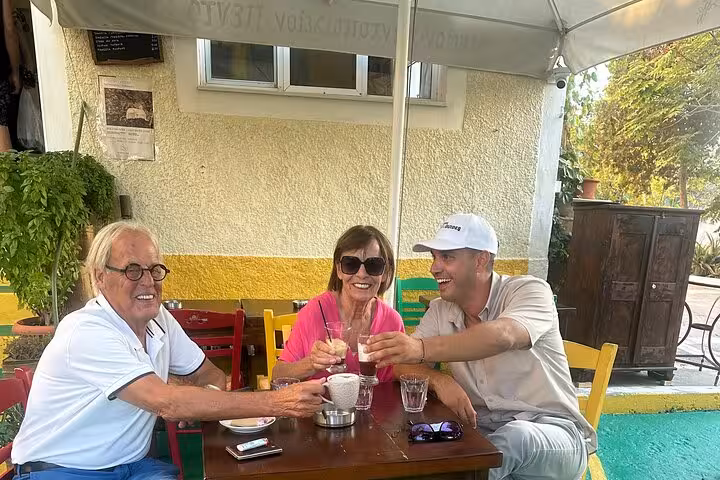 Cruise ship guests toast with local drinks at a Santorini taverna stop on a one-day island tour