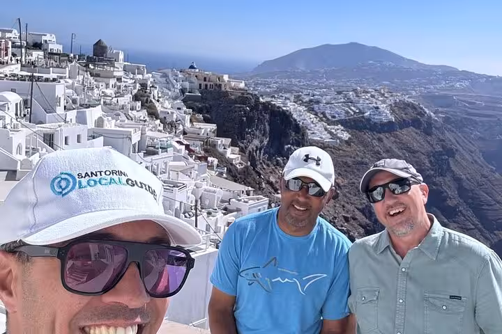 Guests selfie in Santorini Fira, whitewashed cliffside views on Thera 8-hour island tour with lunch and wine