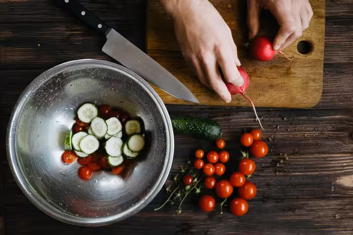 Hands prepping fresh cucumbers, tomatoes and radishes for Greek cooking class, Santorini caldera experience