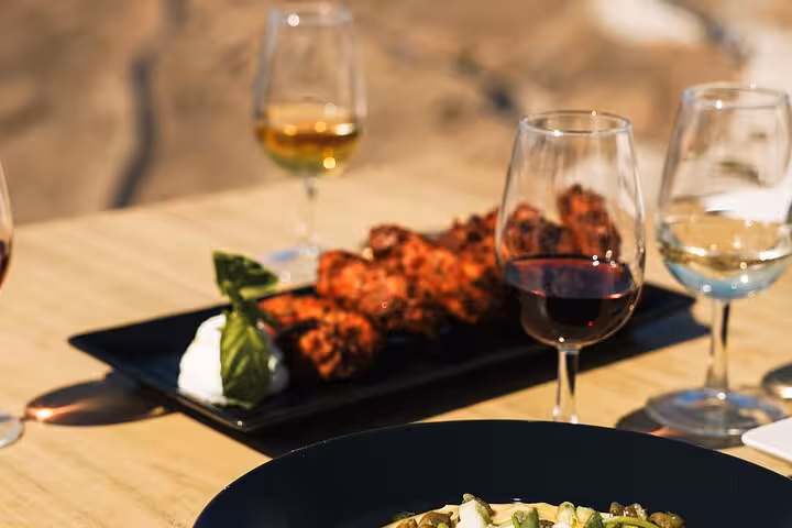 Greek meze and grilled bites with Santorini wine glasses on table, part of honeymoon cooking class and 2 wineries