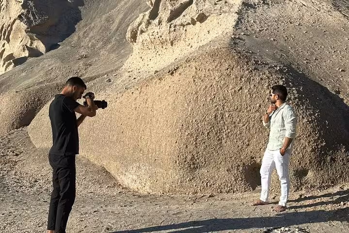 Photographer capturing stylish traveler at Santorini volcanic cliffs on private Instagram photo shooting island tour