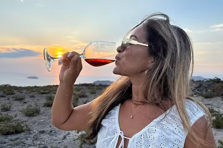 Woman sipping local red wine at Santorini sunset, perfect honeymoon private romantic wine tour experience