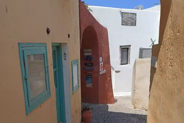 Charming Santorini alley with turquoise doors and cave houses, a stop on the Iconic Highlights Tour