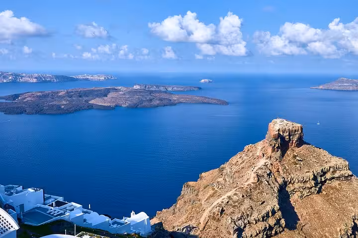 Santorini caldera viewpoint from Imerovigli, blue Aegean sea and volcanic islets on guided tour