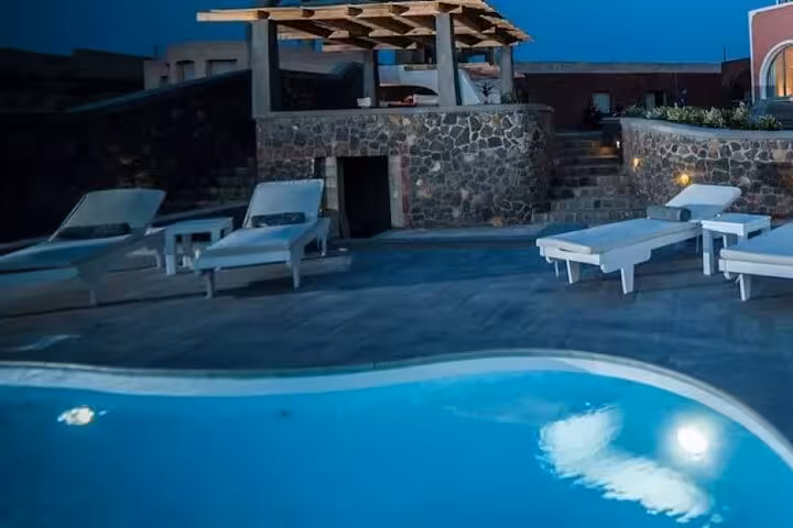 Private Santorini villa pool at night with sun loungers, luxury day getaway stay with transport included