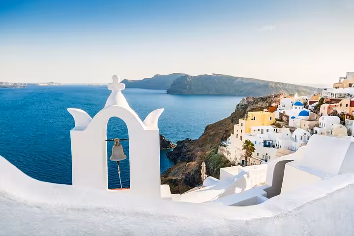 Santorini caldera view with white church bell tower in Oia, highlight of 2-day tour from Athens