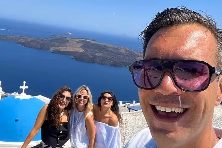Santorini cruise ship day tour selfie in Oia with blue dome church and sweeping caldera views in the background
